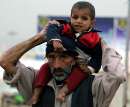 thumb for Kashmiri child sits on his fathers shoulders at refugee camp in Islamabad